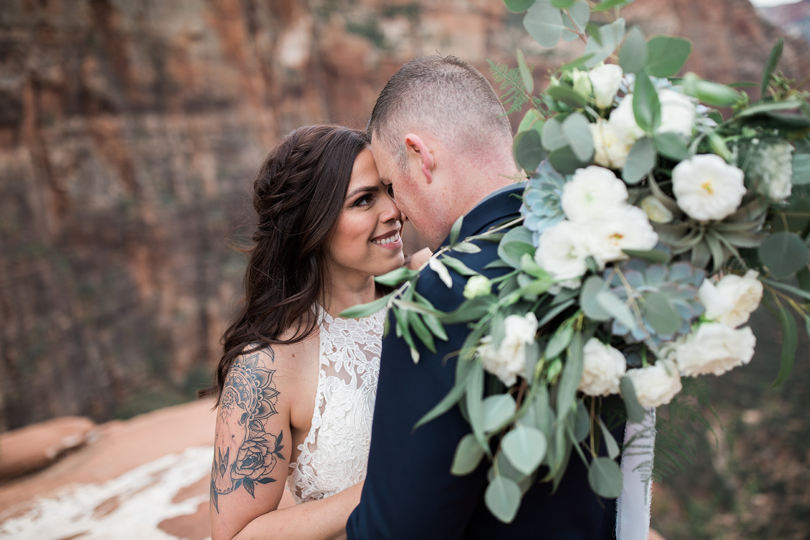 bride and groom touch foreheads, flowers over shoulder