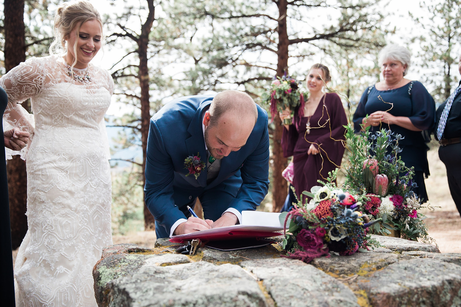bride and groom sign wedding certificate after being married in rocky mountain colorado outdoor elopement