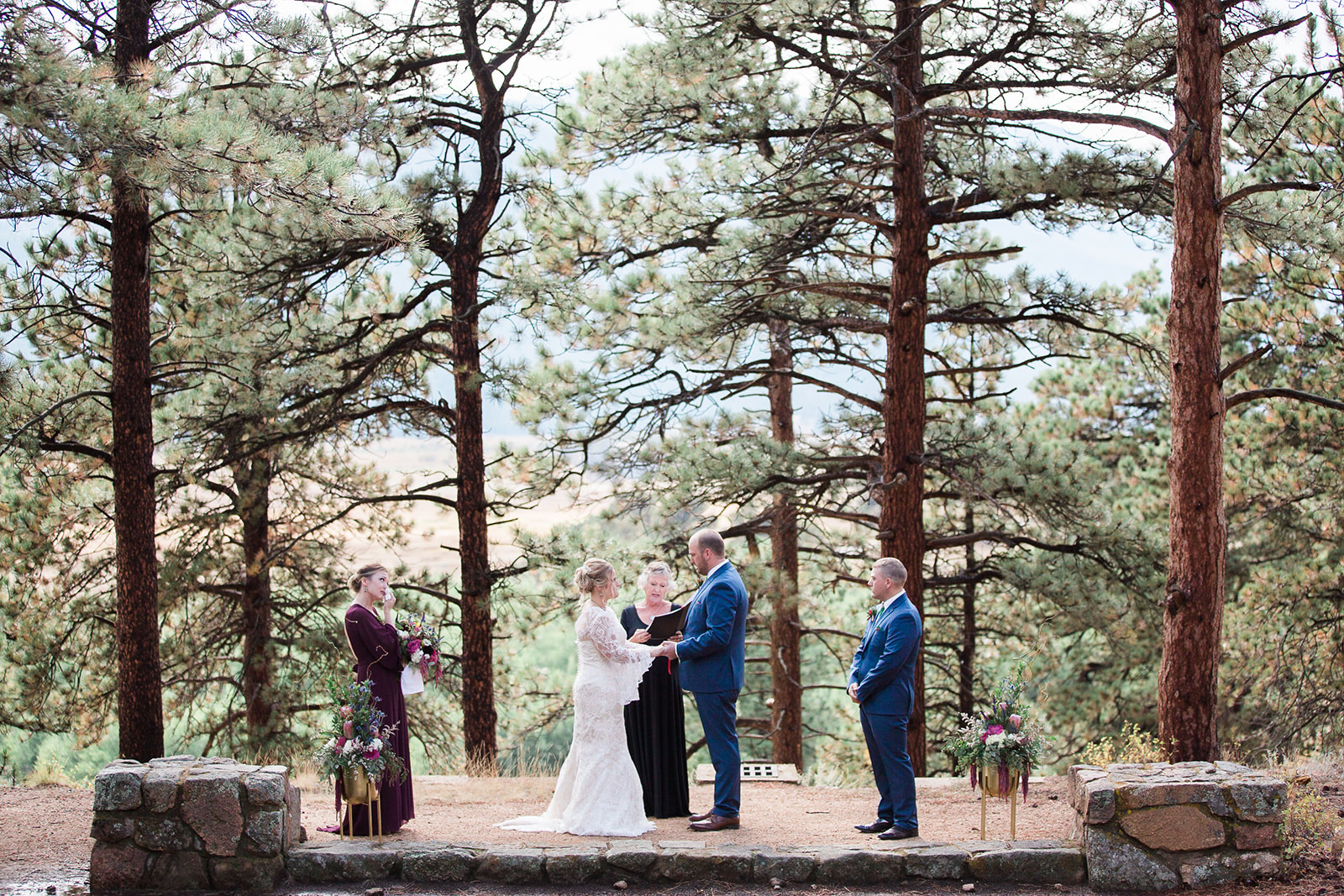 bride and groom stand under pine trees in rocky mountain national park