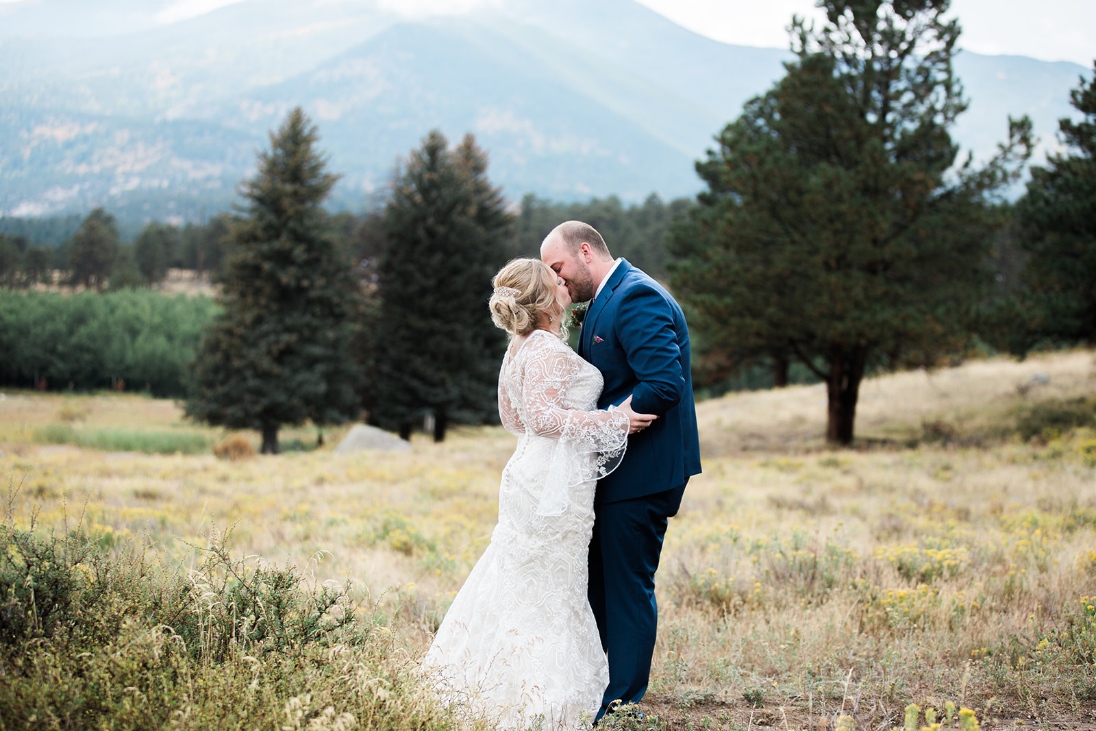 groom kisses bride in rocky mountain national park field before elopement 