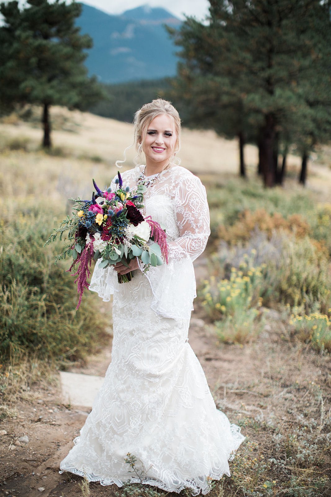 bride standing in stunning mountain field in rocky mountain national park elopement