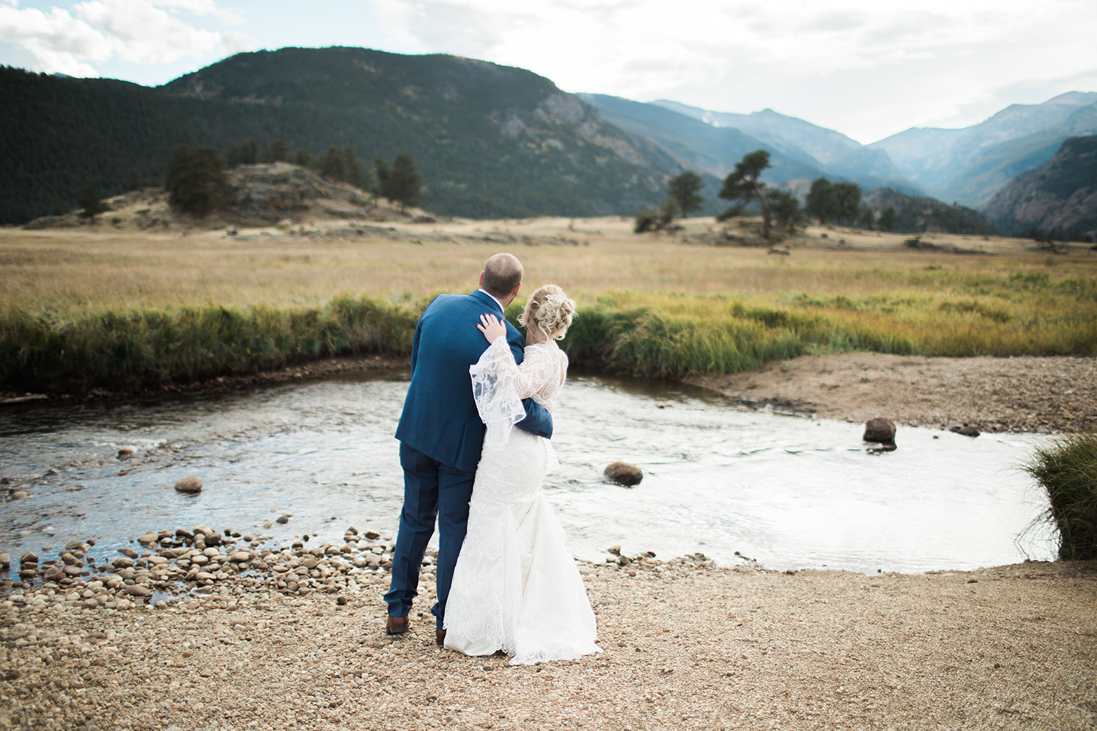 bride and groom kissing in front of rocky mountain river