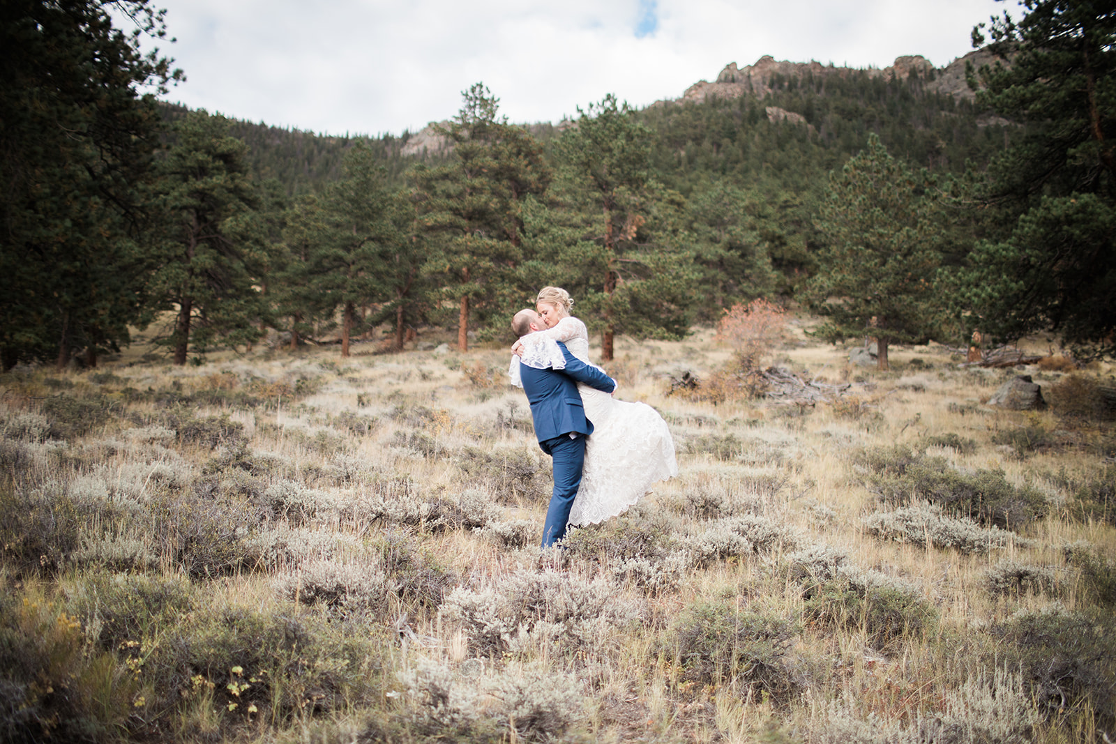 bride and groom walk in front of stunning rocky mountain national park vista