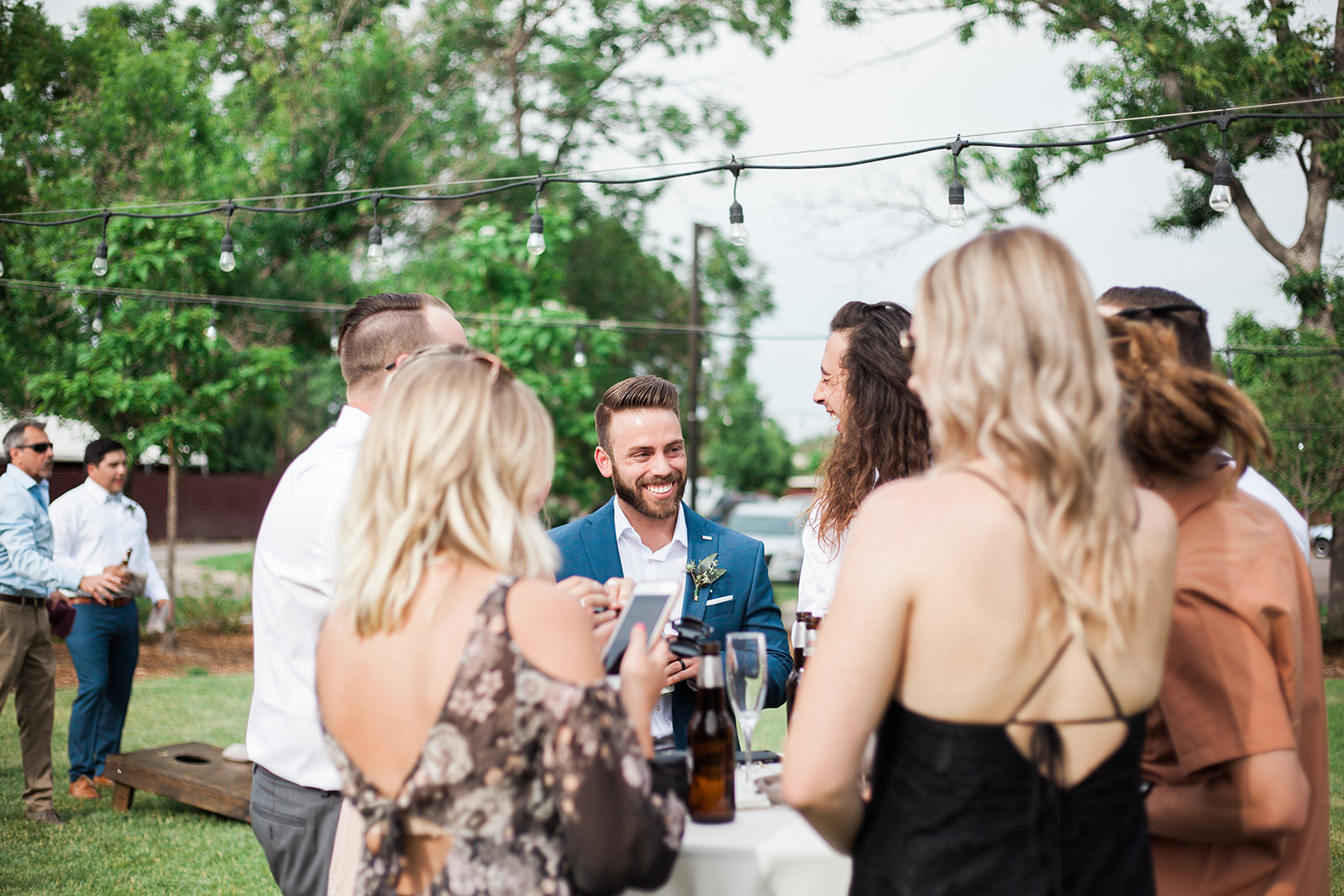 groom laughing with friends at reception cocktail hour