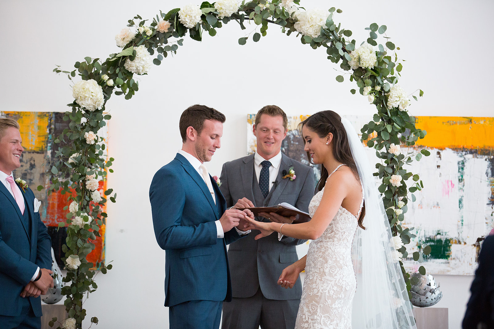 groom puts ring on bride's finger at Denver wedding ceremony