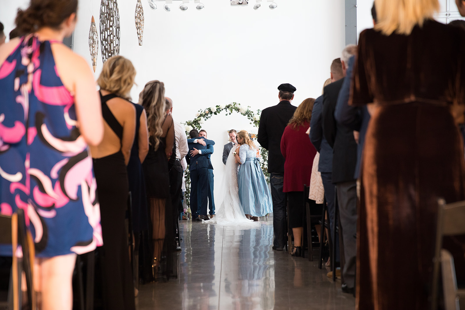 bride hugs mom at top of aisle at wedding ceremony