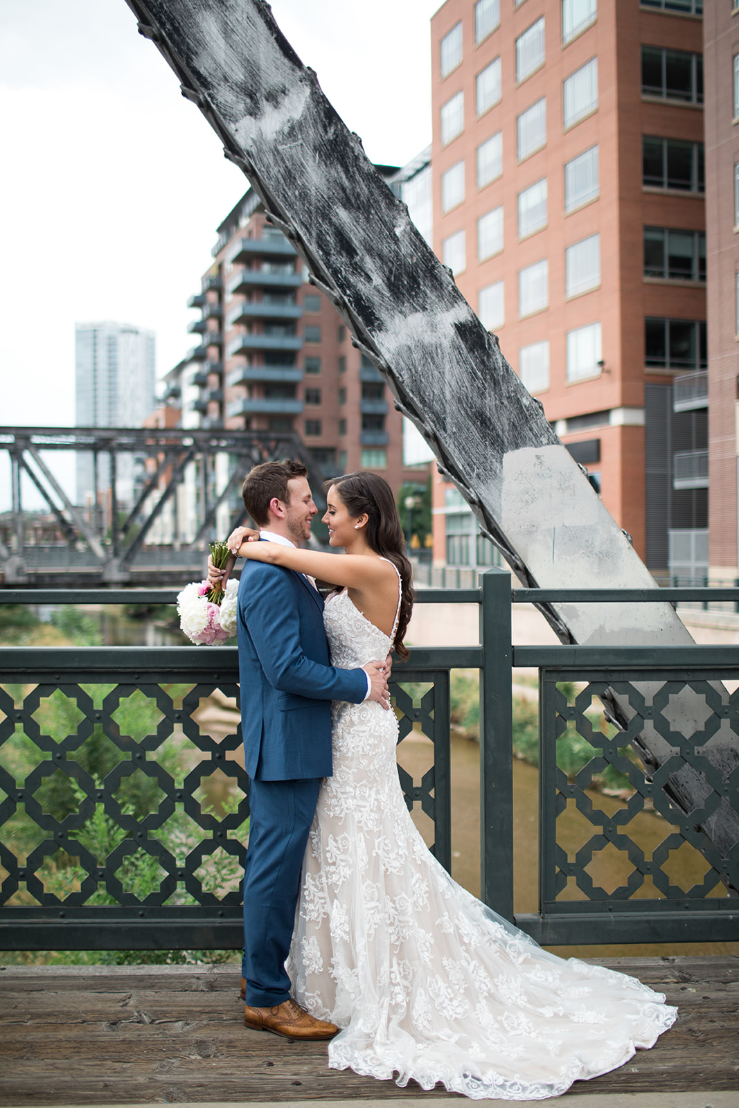 bride and groom hugging on bridge overlooking Denver skyline