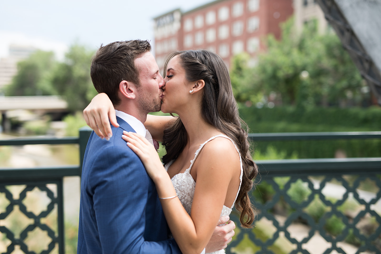 bride and groom kissing on bridge in downtown denver