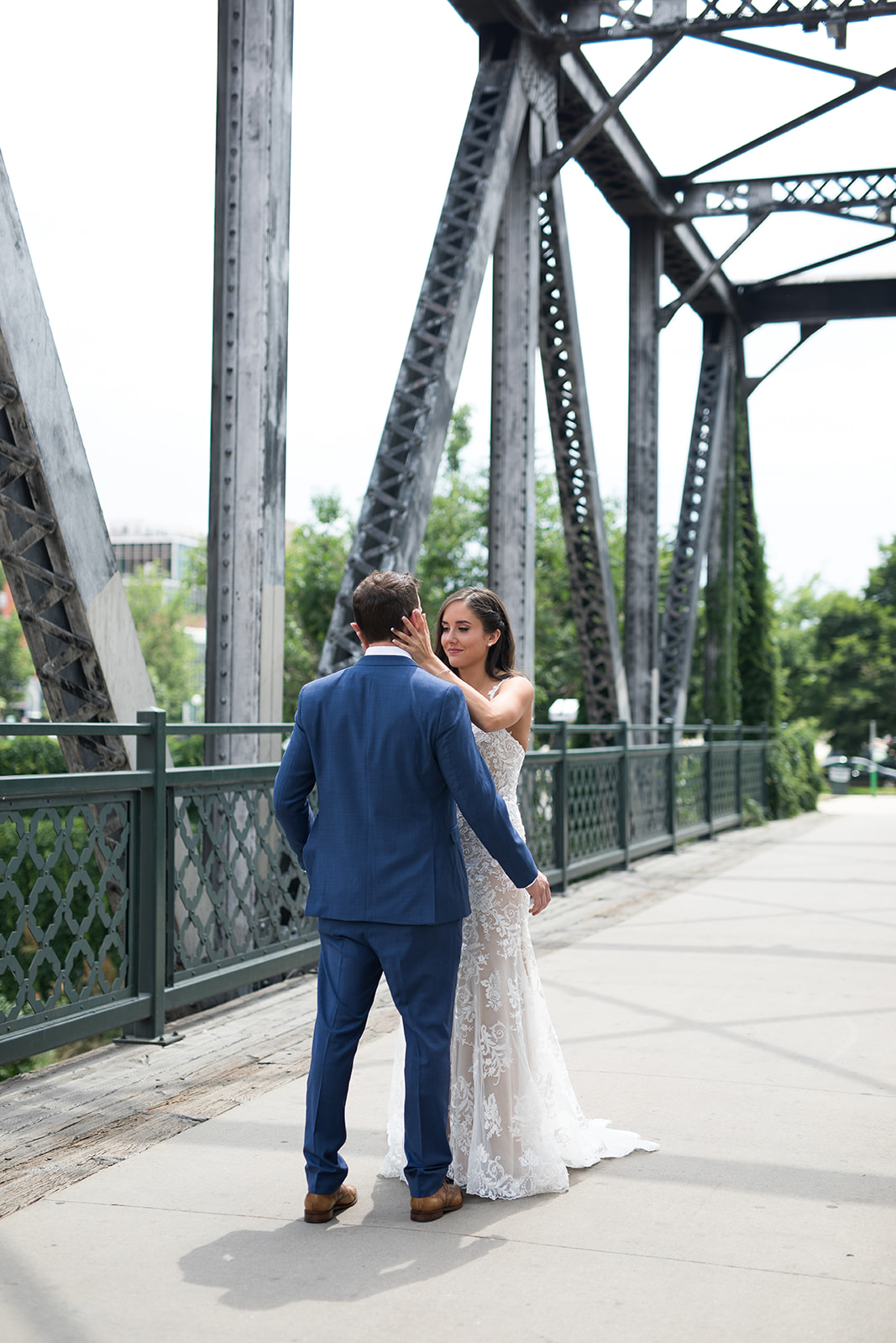 bride holding groom's face on bridge in downtown Denver