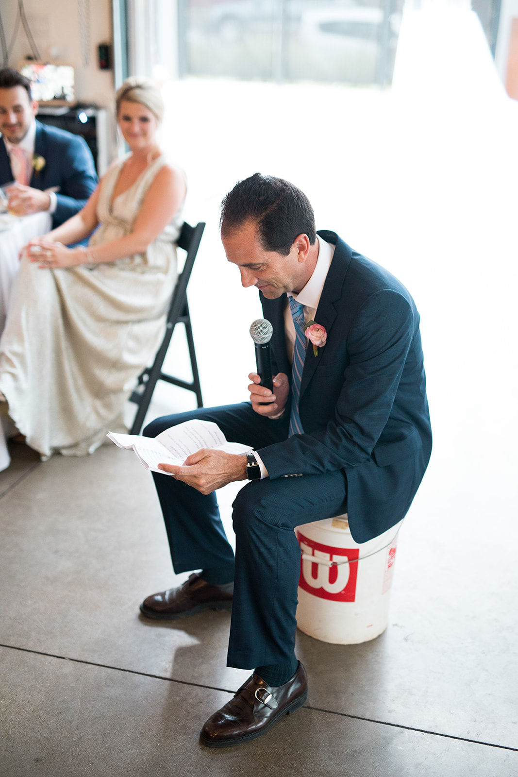 guest giving speech sitting on a bucket at denver wedding reception