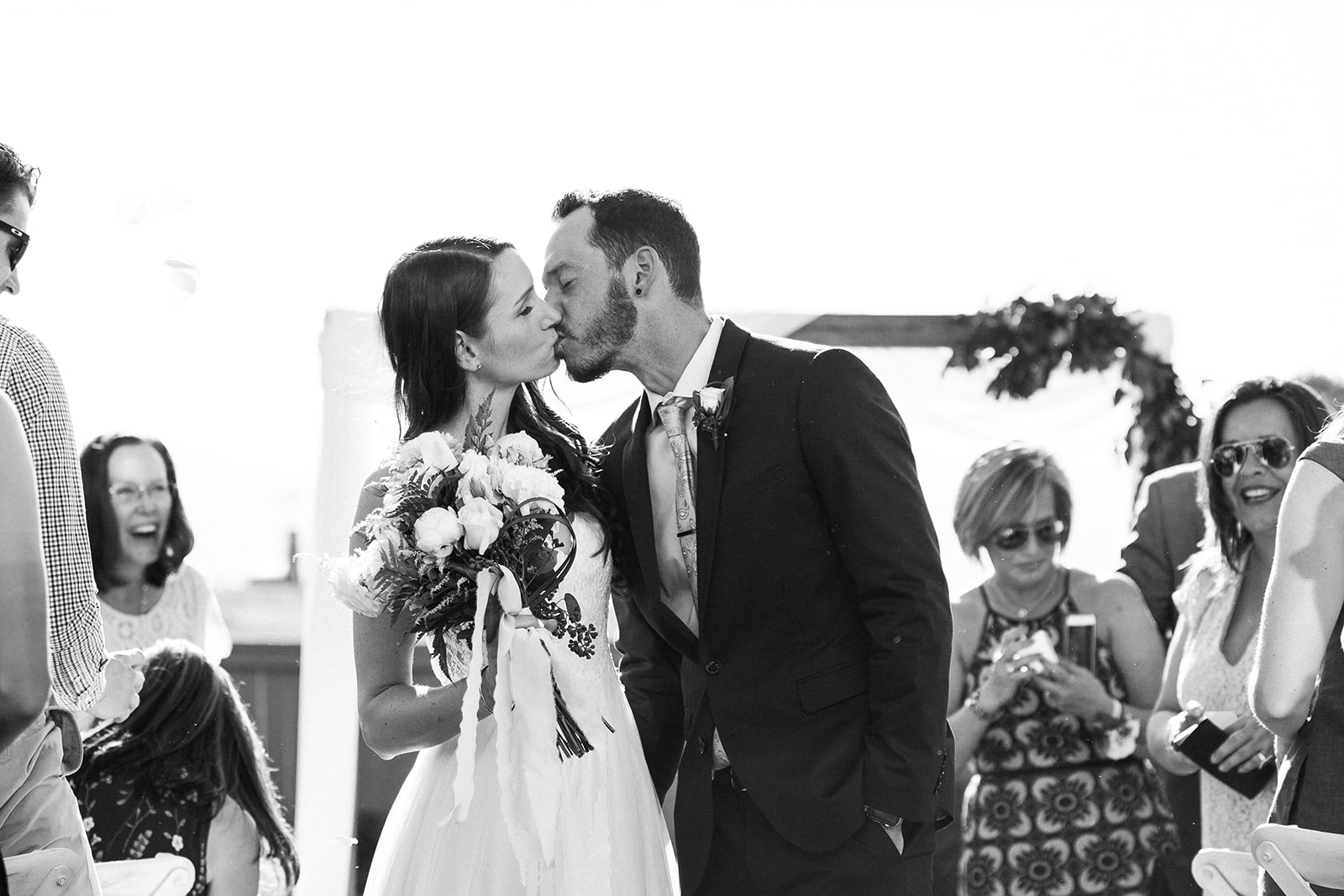 bride and groom kiss as they walk down aisle after getting married