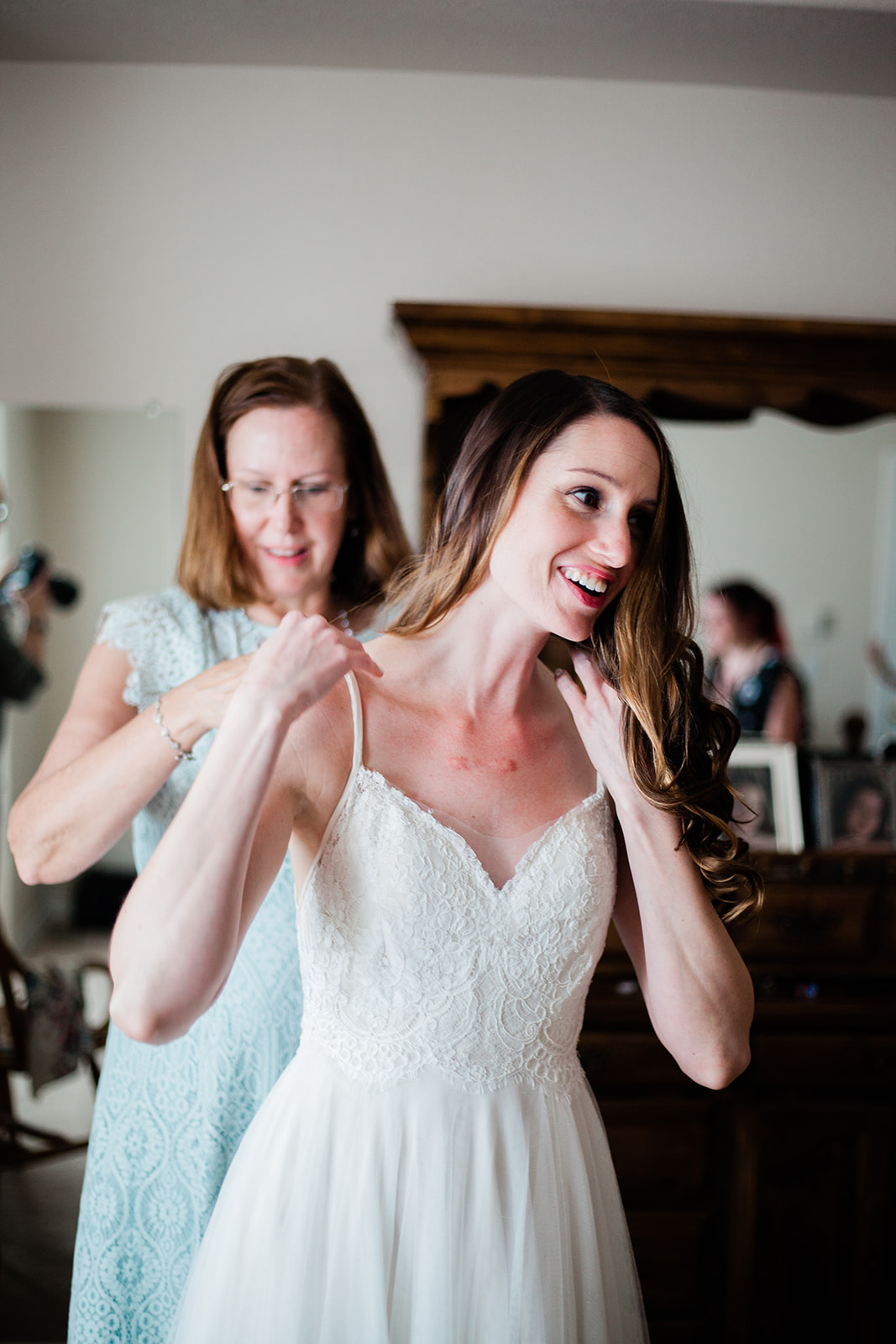 bride getting in wedding dress with mother's help