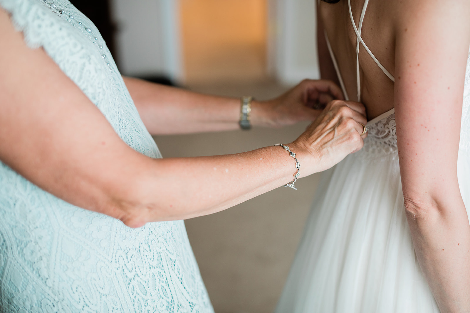 mother's hands tying wedding dress ribbon