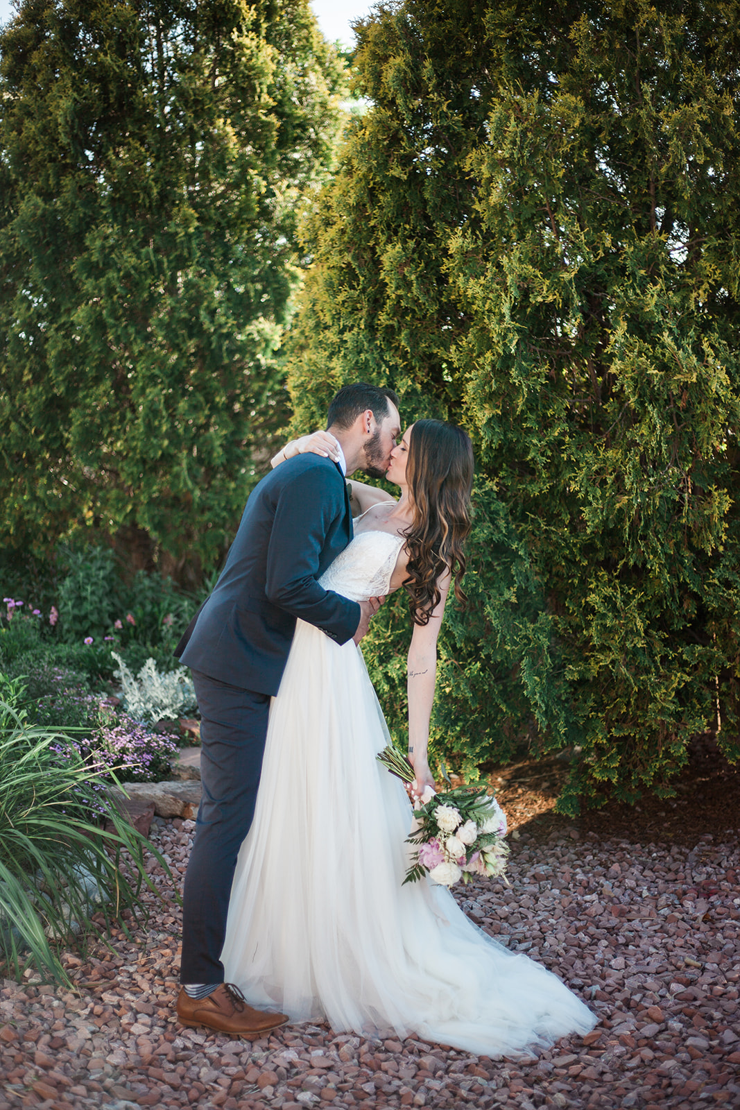 groom dipping bride in front of pine trees in intimate backyard portrait