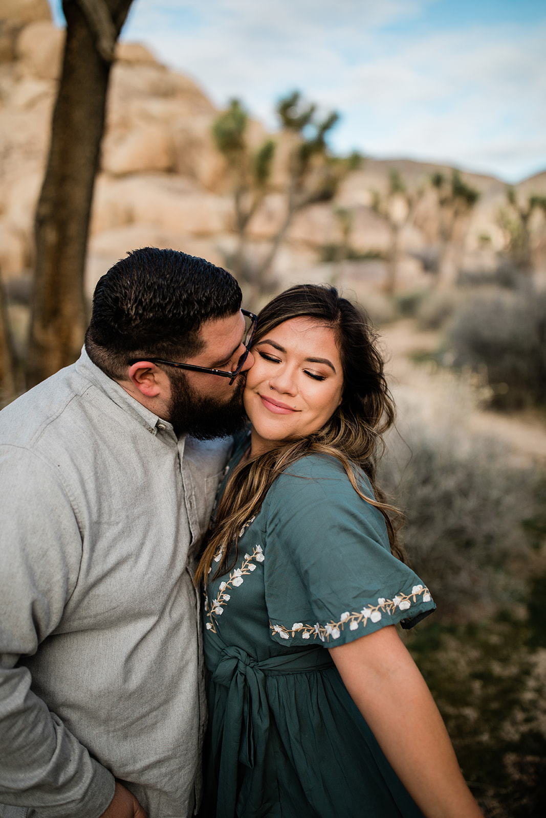 man kisses woman on the cheek in front of a desert background
