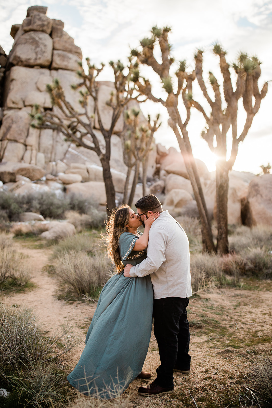 engaged couple kissing at desert sunset