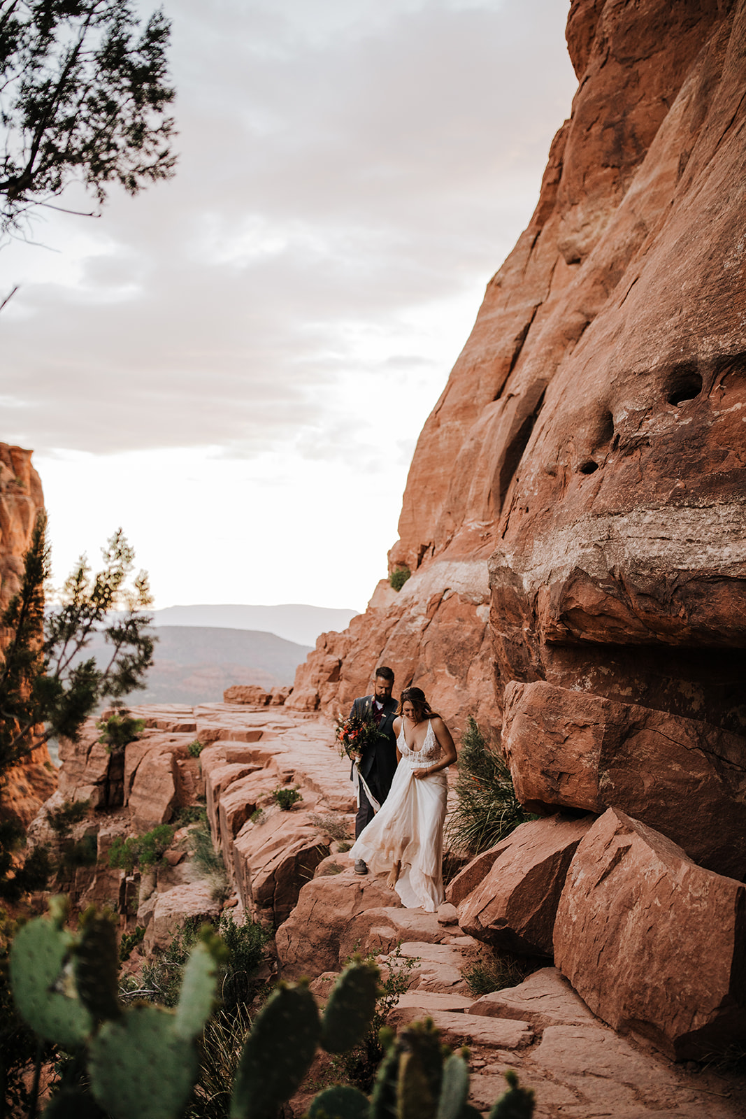 bride leads groom down a rock trail in the Sedona Arizona desert