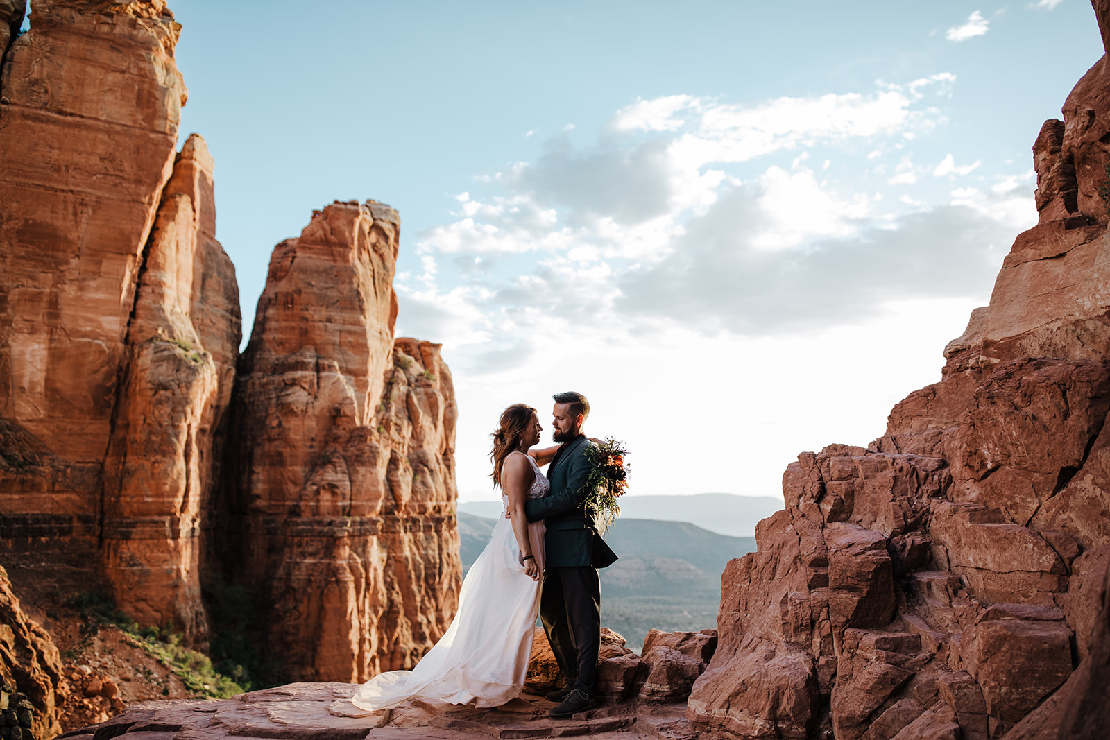 groom and bride in front of dramatic Sedona Arizona rock outcropping