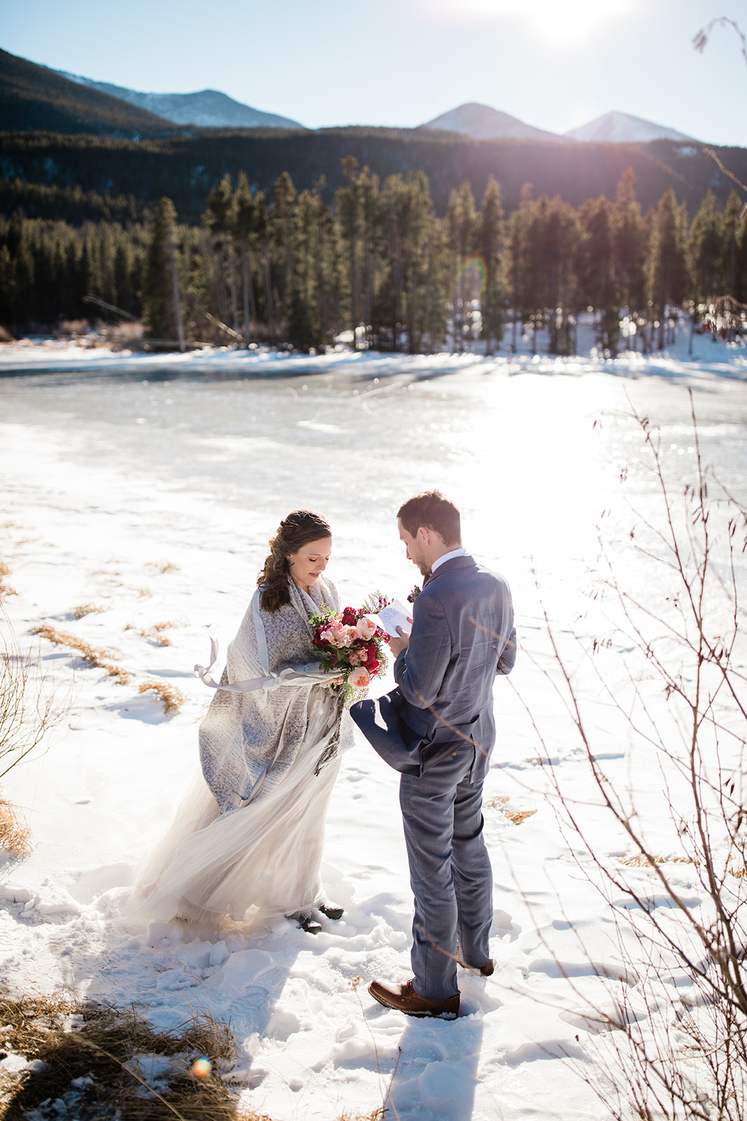 bride and groom read vows on frozen Sprague Lake for elopement