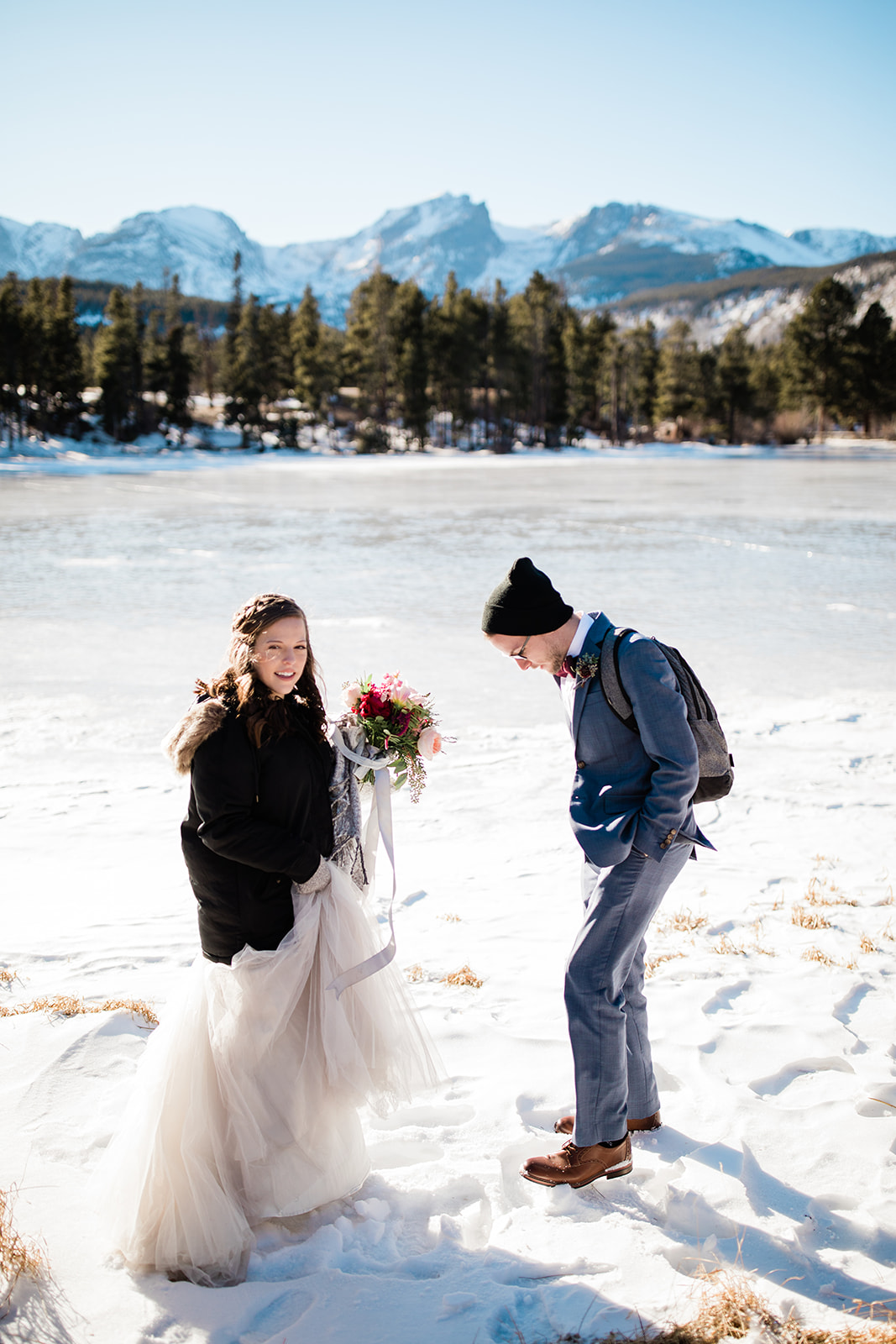 Bride and groom hike out onto frozen Sprague lake for outdoor Colorado mountain winter elopement