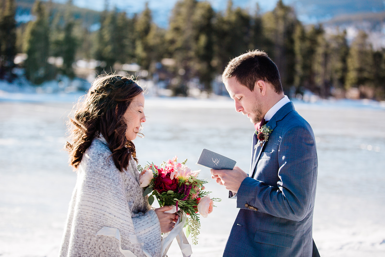 bride and groom read vows on frozen Sprague Lake for elopement
