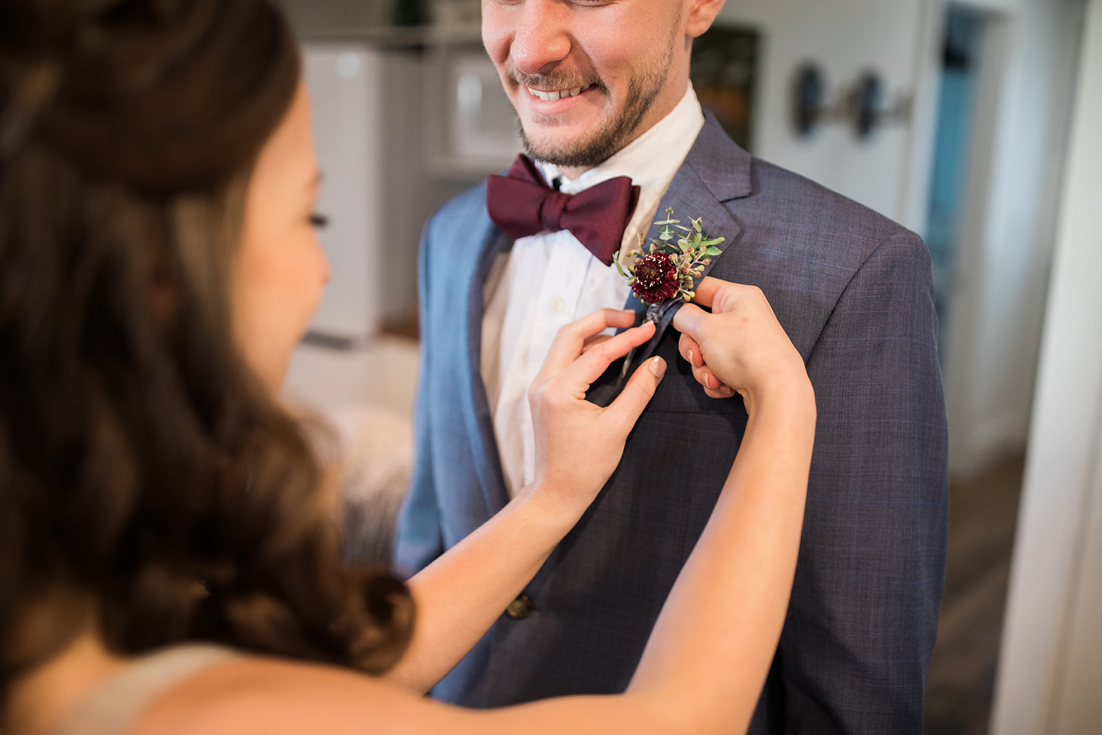 bride pins boutonniere on to groom before elopement