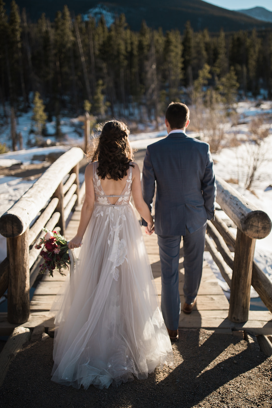 bride and groom pose on frozen Colorado mountain lake