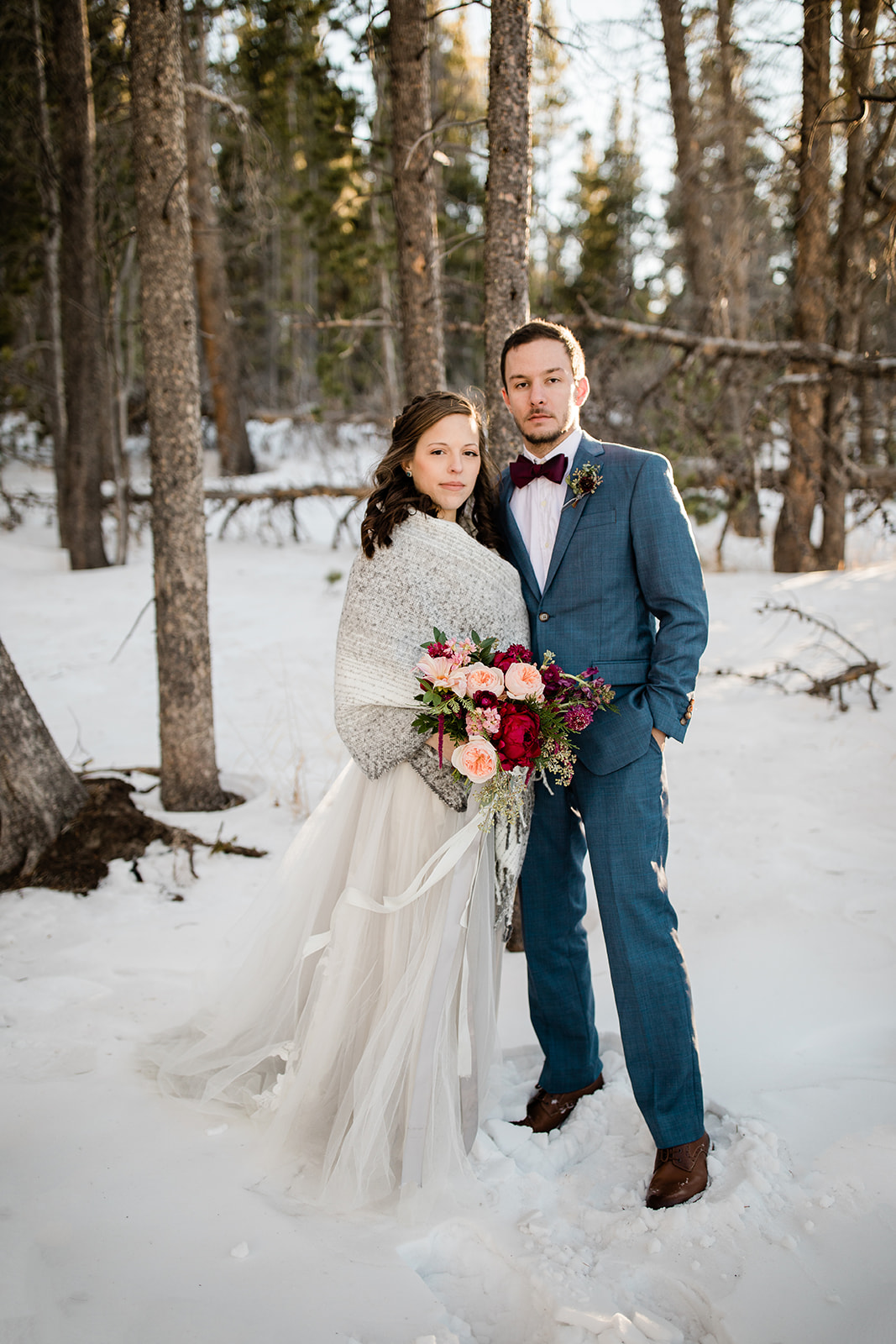 bride and groom in snowy winter woods after Colorado mountain elopement