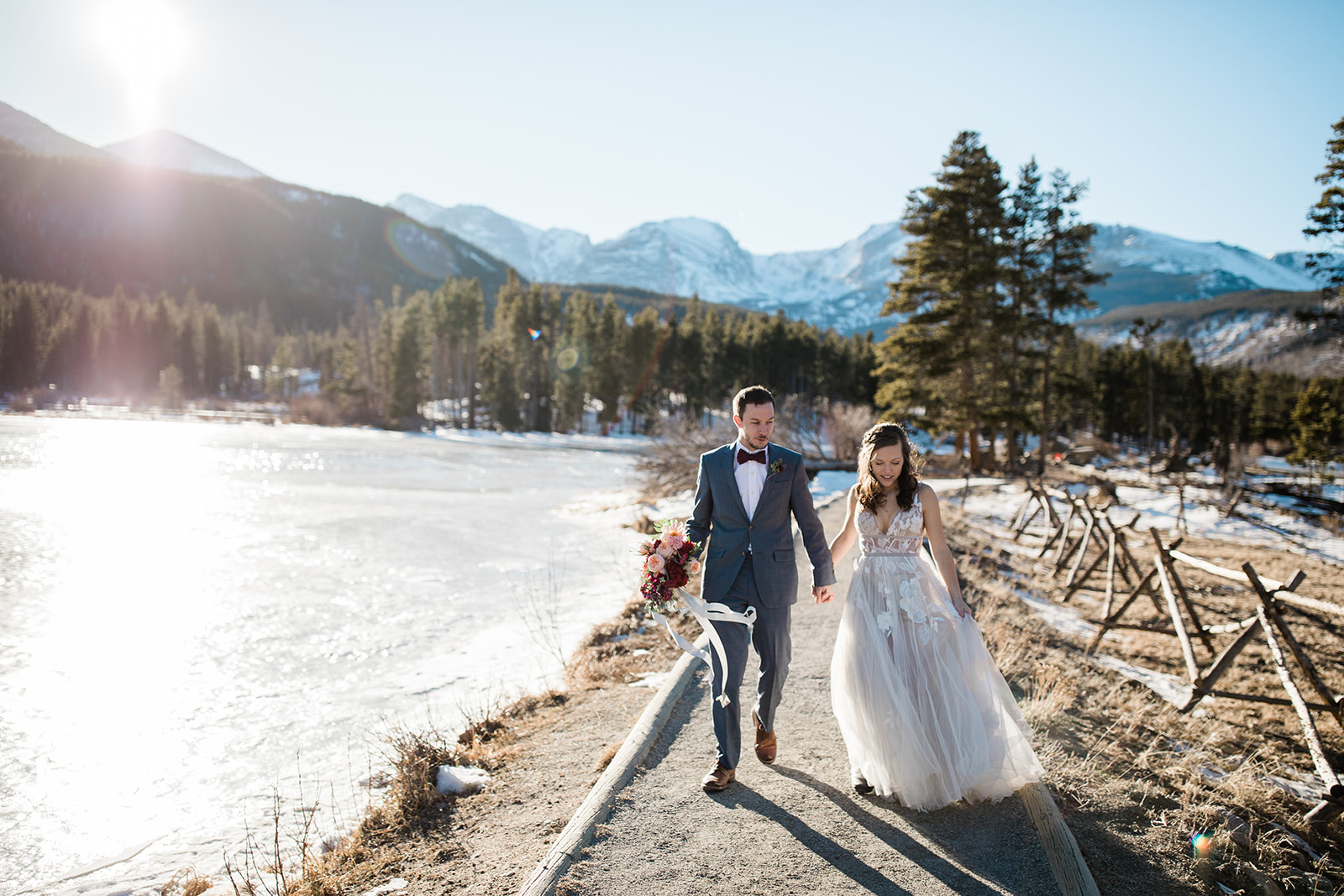 bride and groom walk next to Sprague Lake after elopement ceremony in the winter