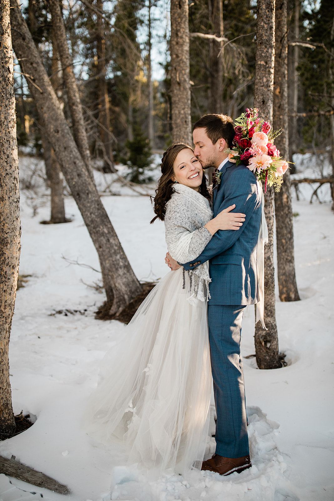 groom kisses bride in woods outside Sprague Lake
