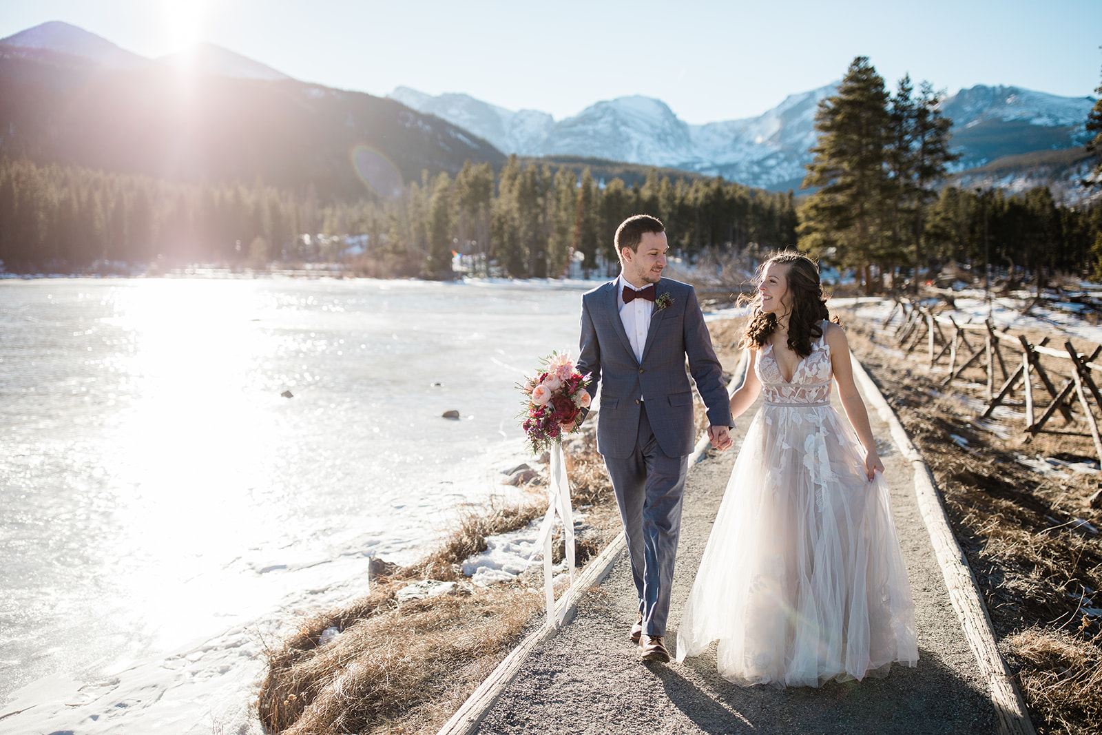 bride and groom walk next to Sprague Lake after elopement ceremony in the winter
