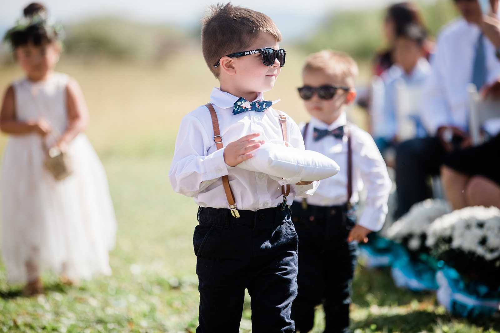ring bearer and flower girl walks down aisle in outdoor Colorado mountain ranch wedding