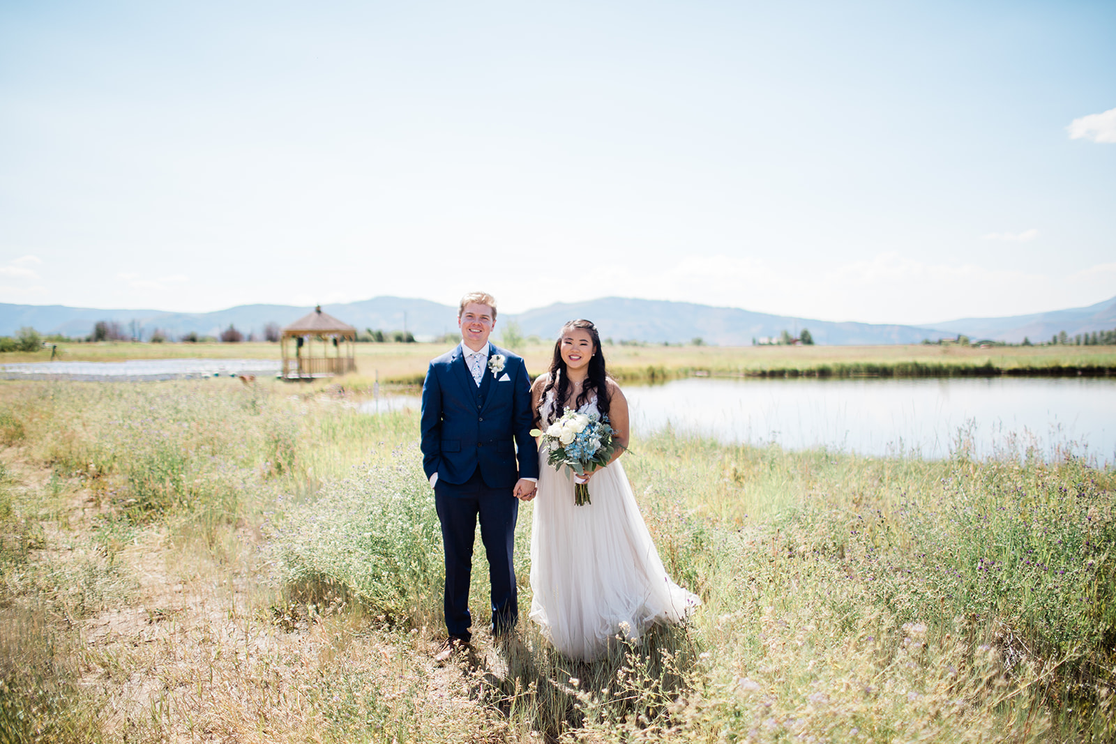 bride and groom stand in front of lake at the Crestview Ranch in Granby, Colorado