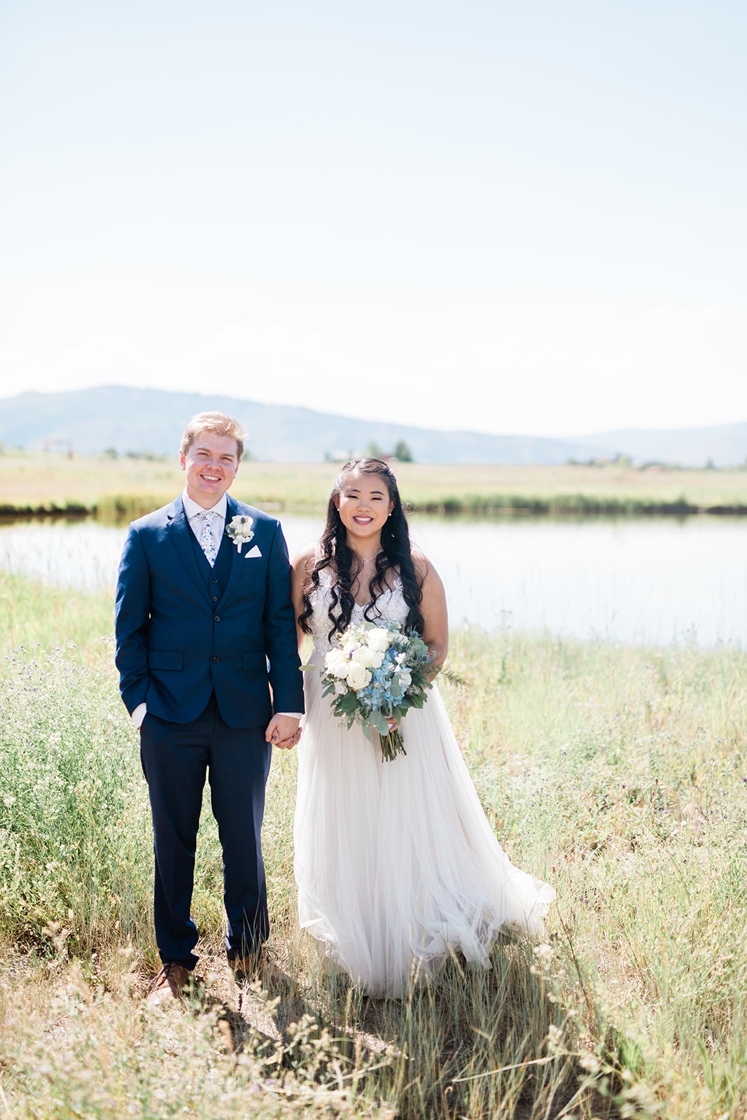 bride and groom stand in front of lake at the Crestview Ranch in Granby, Colorado