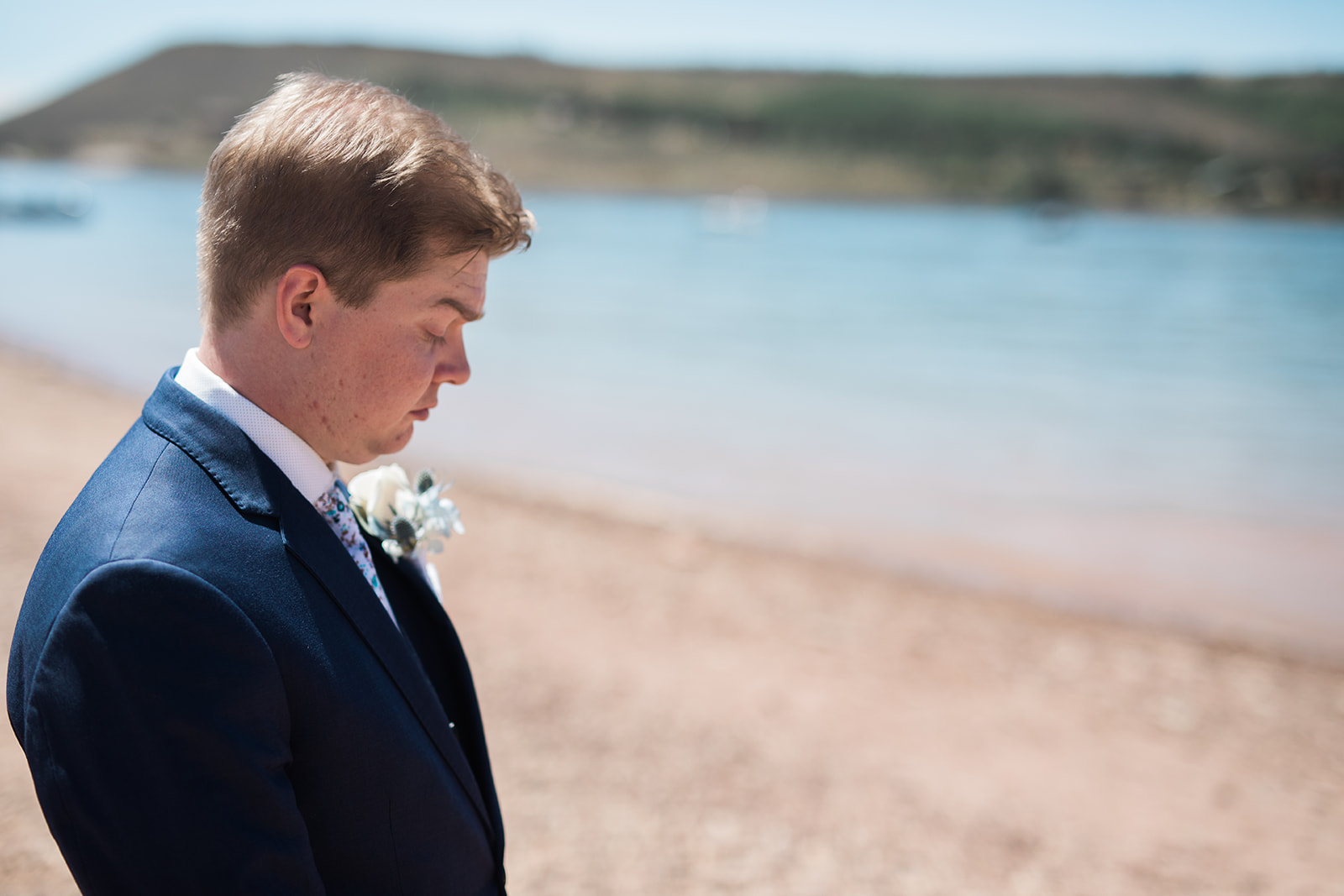 groom waits for bride at gorgeous lake near the Crestview Ranch in Granby Colorado