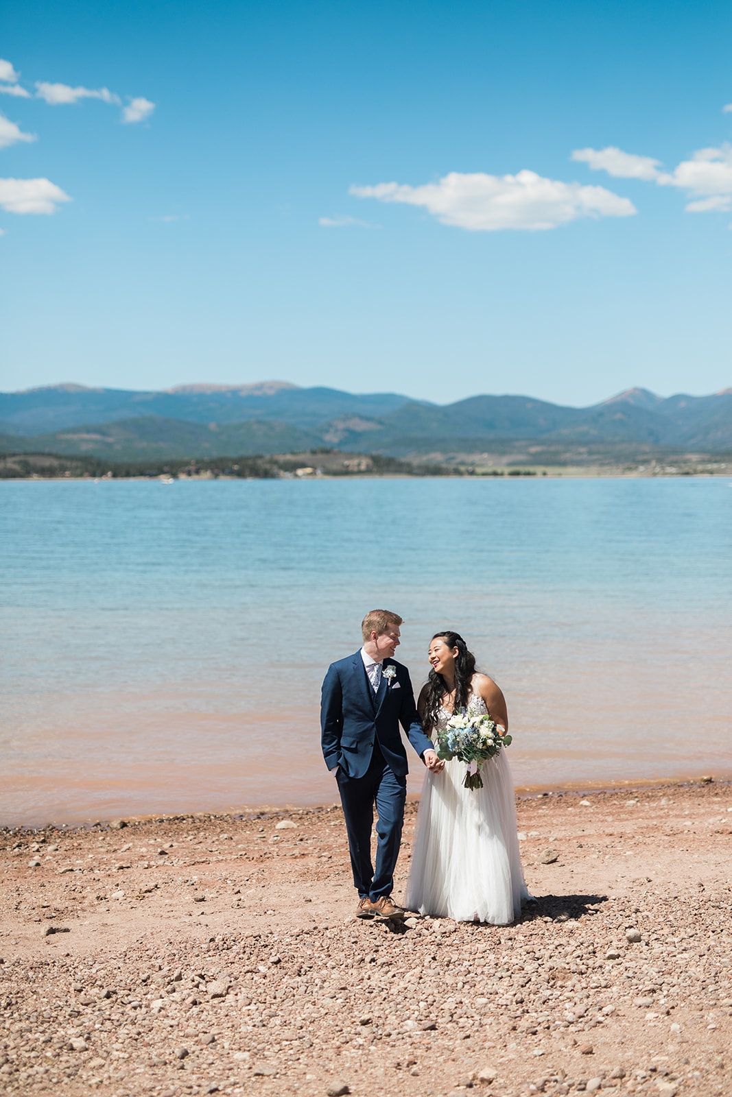 bride and groom look at lake in Colorado mountains