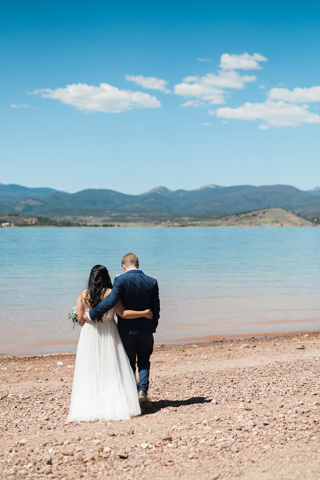 bride and groom look at lake in Colorado mountains