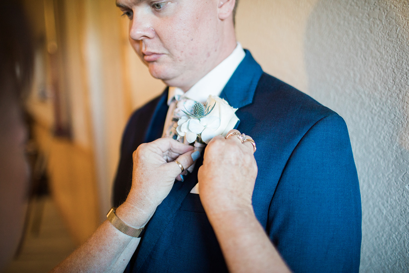 groom gets boutonniere pinned to suit jacket