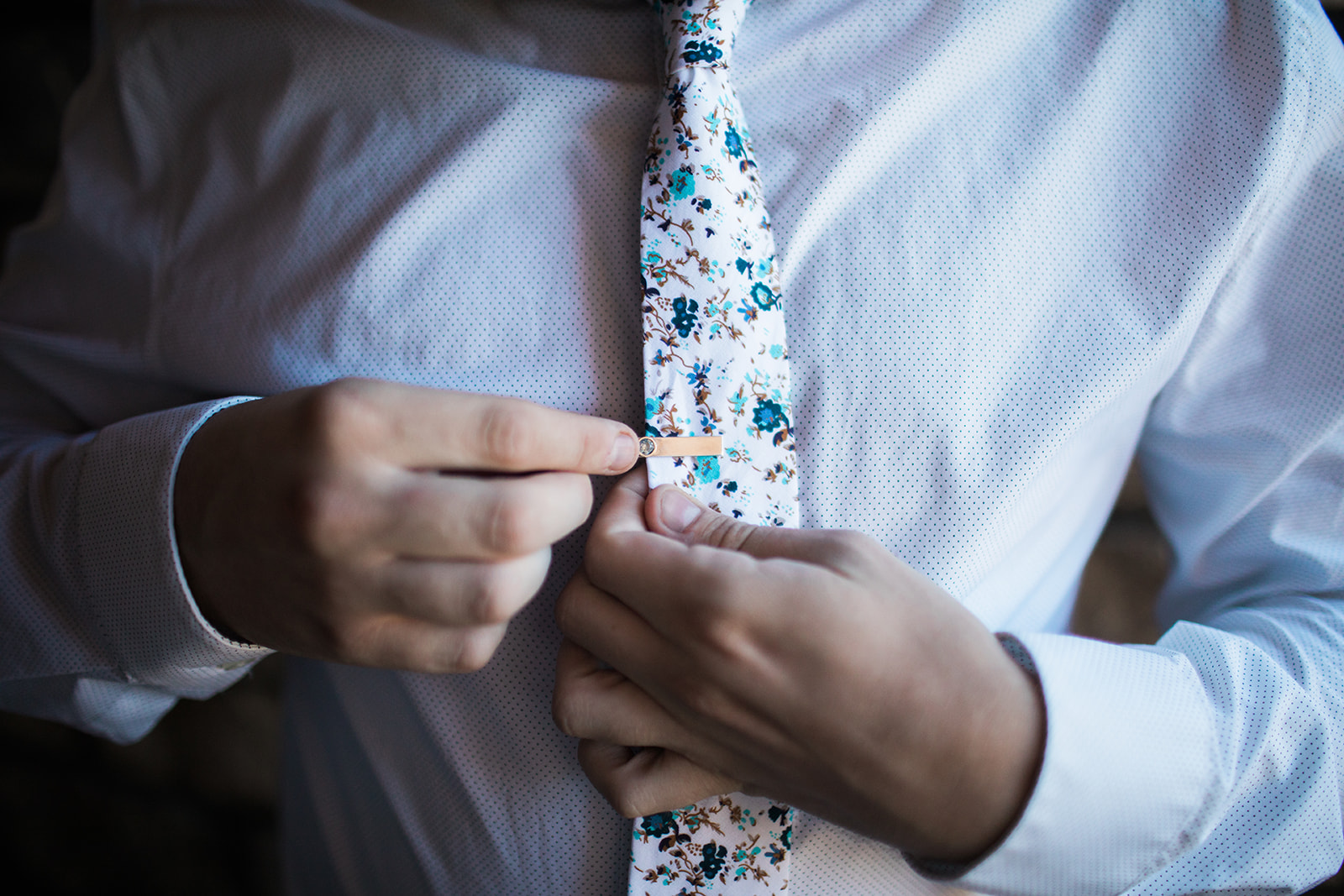 groom puts tie tack on tie for Colorado mountain wedding