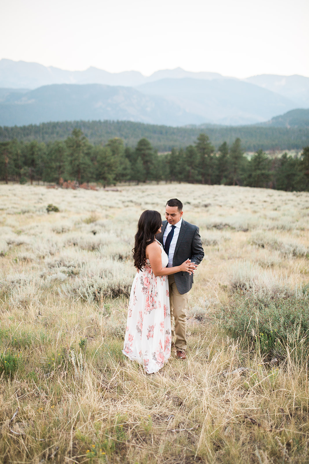 couple walks through RMNP meadow at sunset