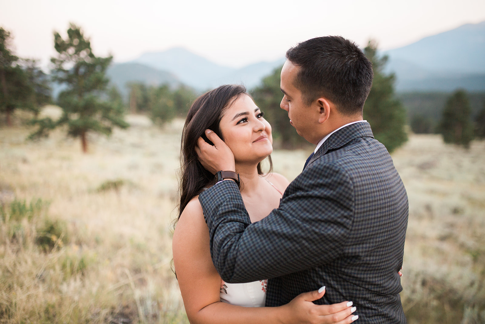 couple walks through RMNP meadow at sunset