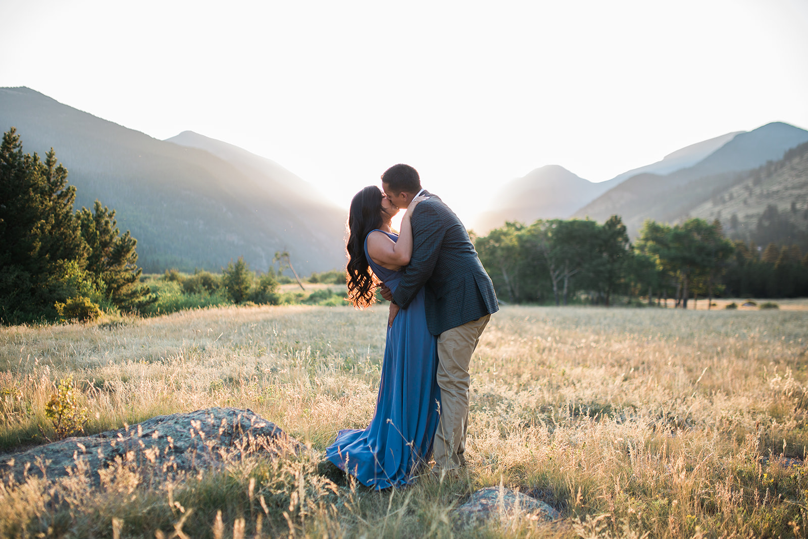 couple kisses in meadow during RMNP sunset