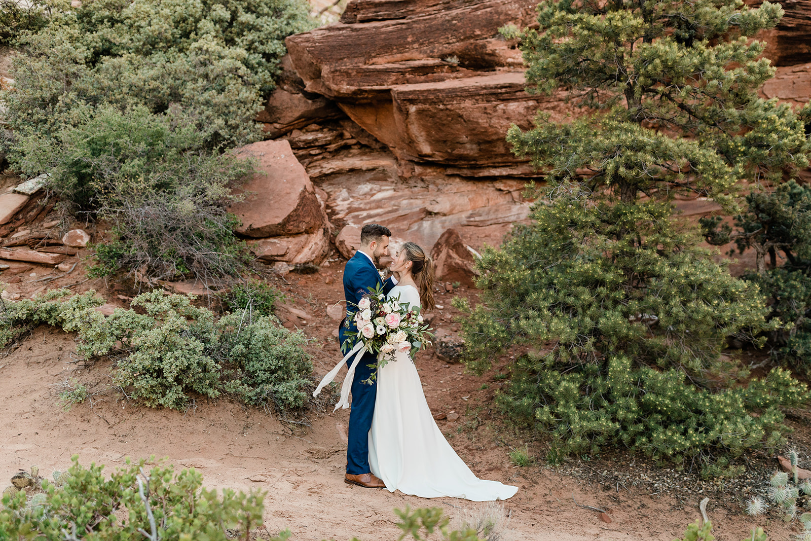 Nick and Kate kissing in front of red sandstone rocks in Zion