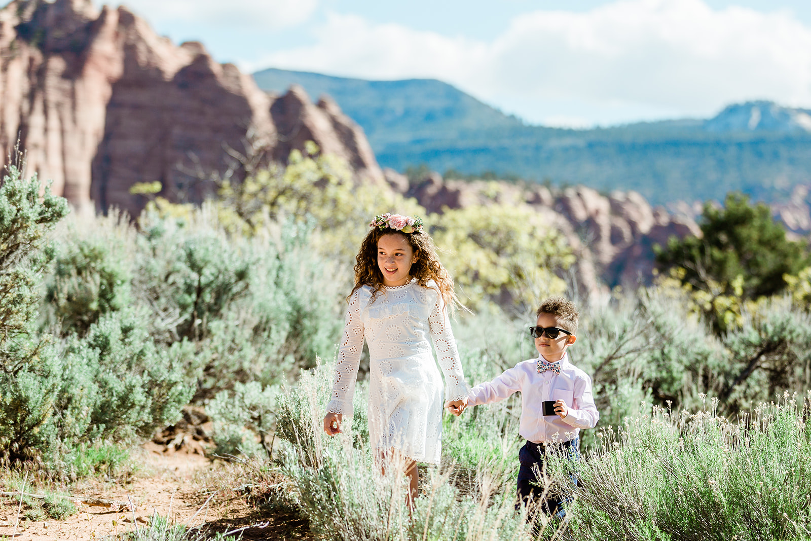 flower girl and ring bearer walk through landscape to elopement site