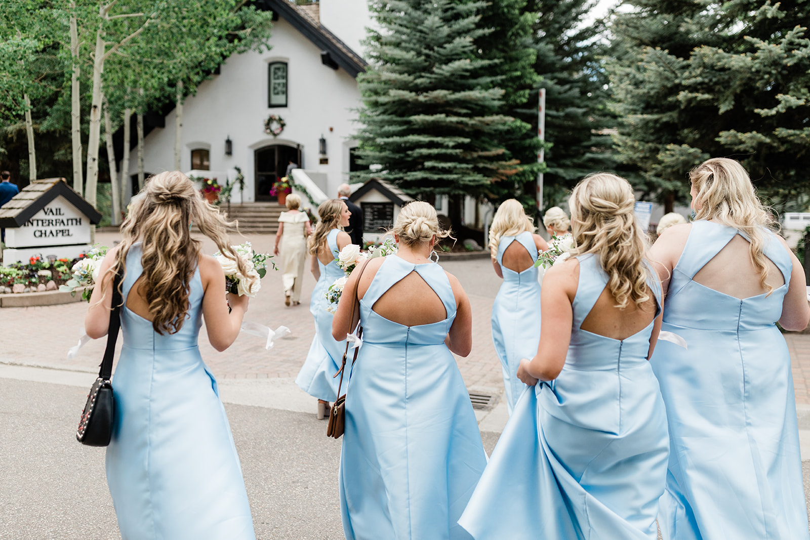 bride and bridesmaids walk to chapel in downtown Vail Colorado