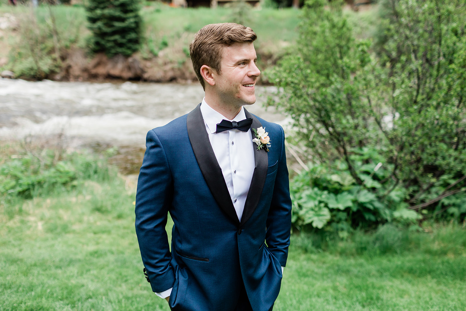 groom portrait by river in Colorado mountains