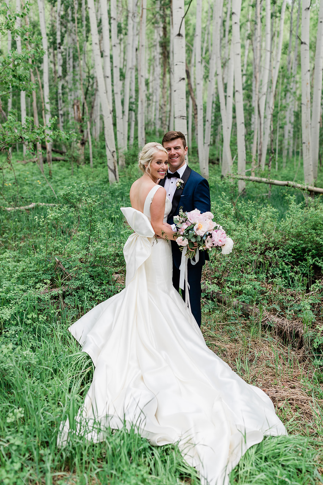 Vail bride and groom pose in strand of green aspen trees