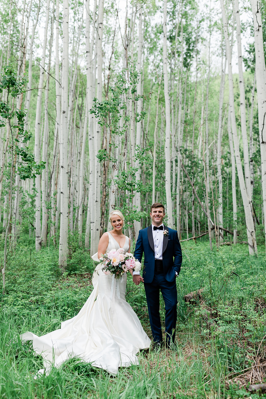 Vail bride and groom pose in strand of green aspen trees
