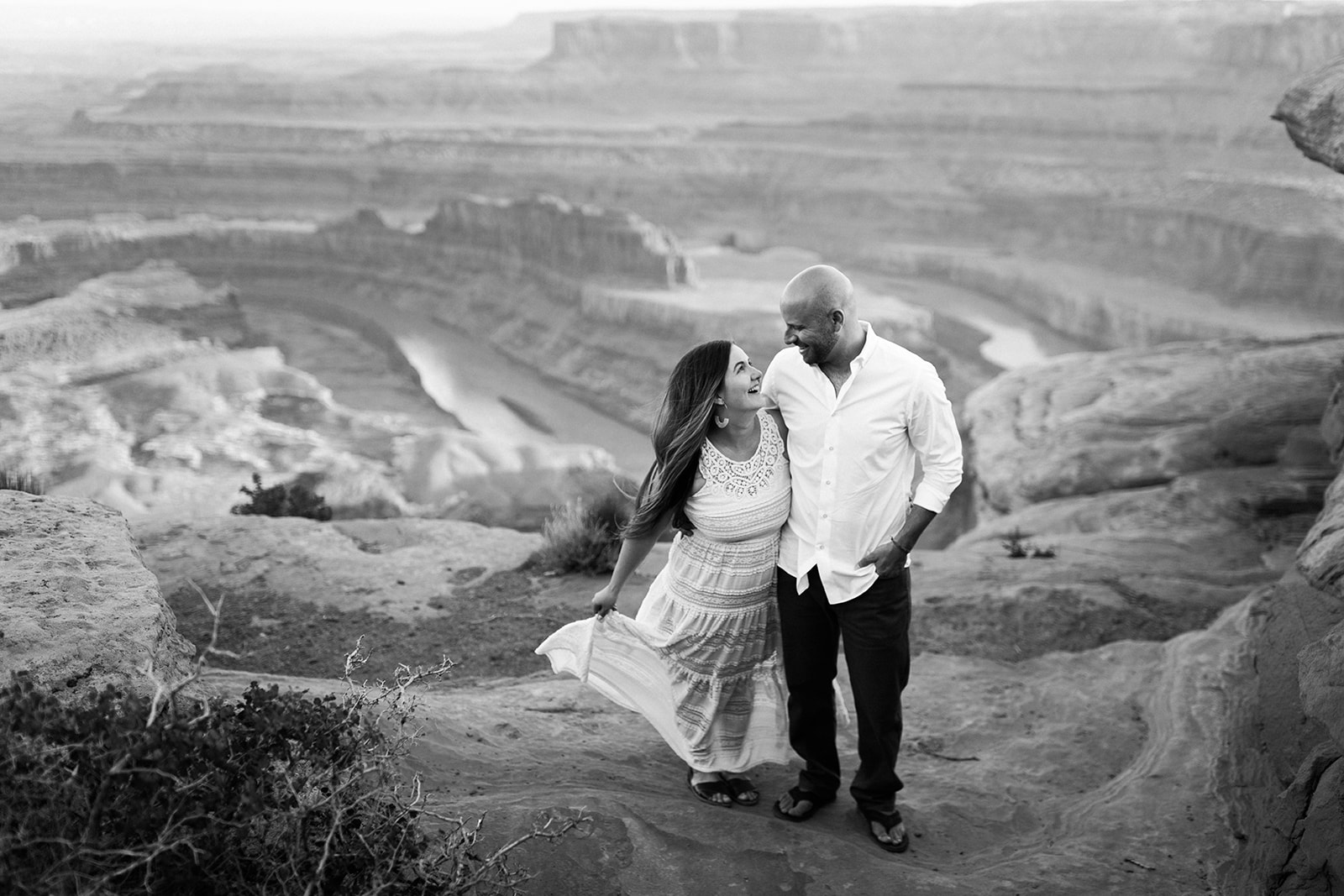 beautiful couple stands overlooking a dramatic Moab dessert vista