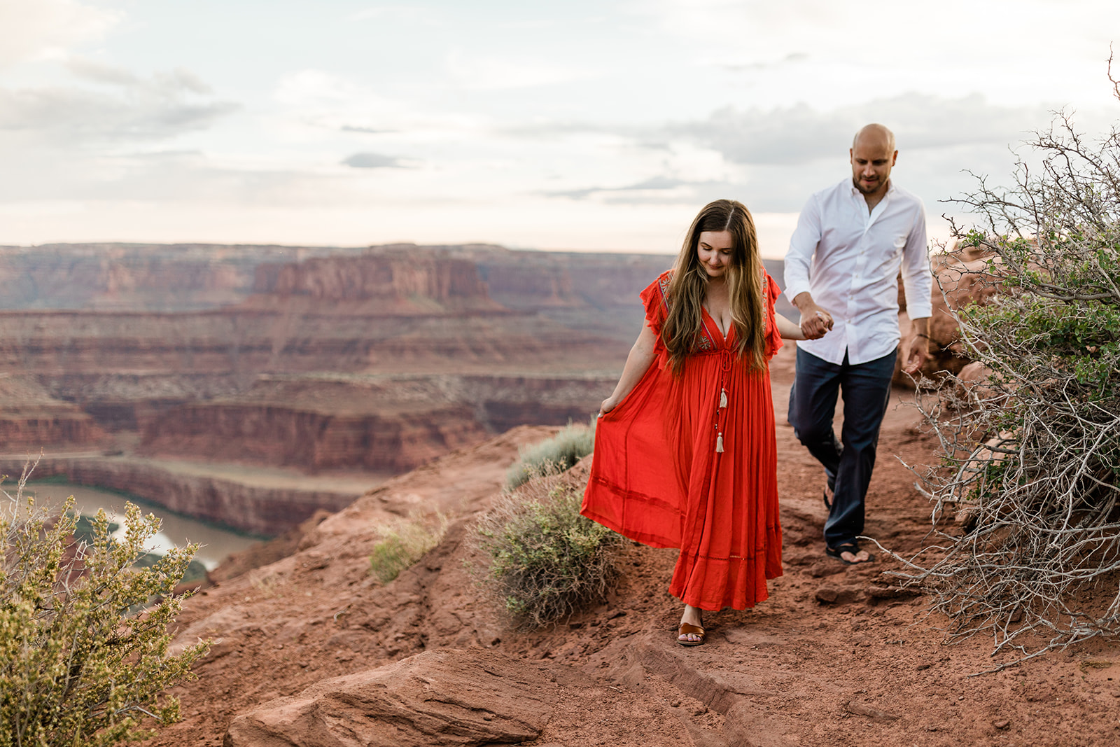 woman in red dress kisses fiancee in Moab mountain adventure session